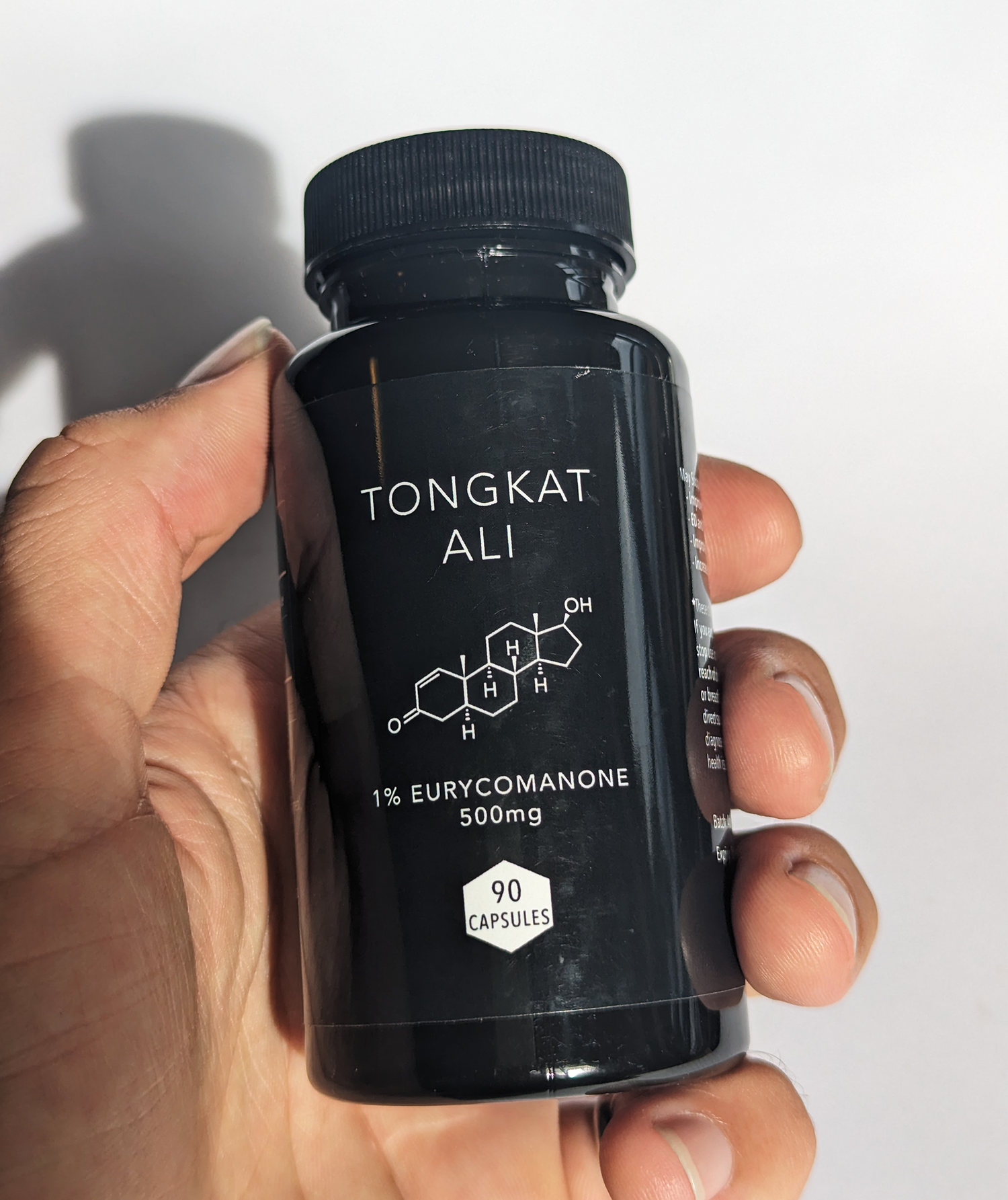 Tongkat ali capsule bottle held in hand.